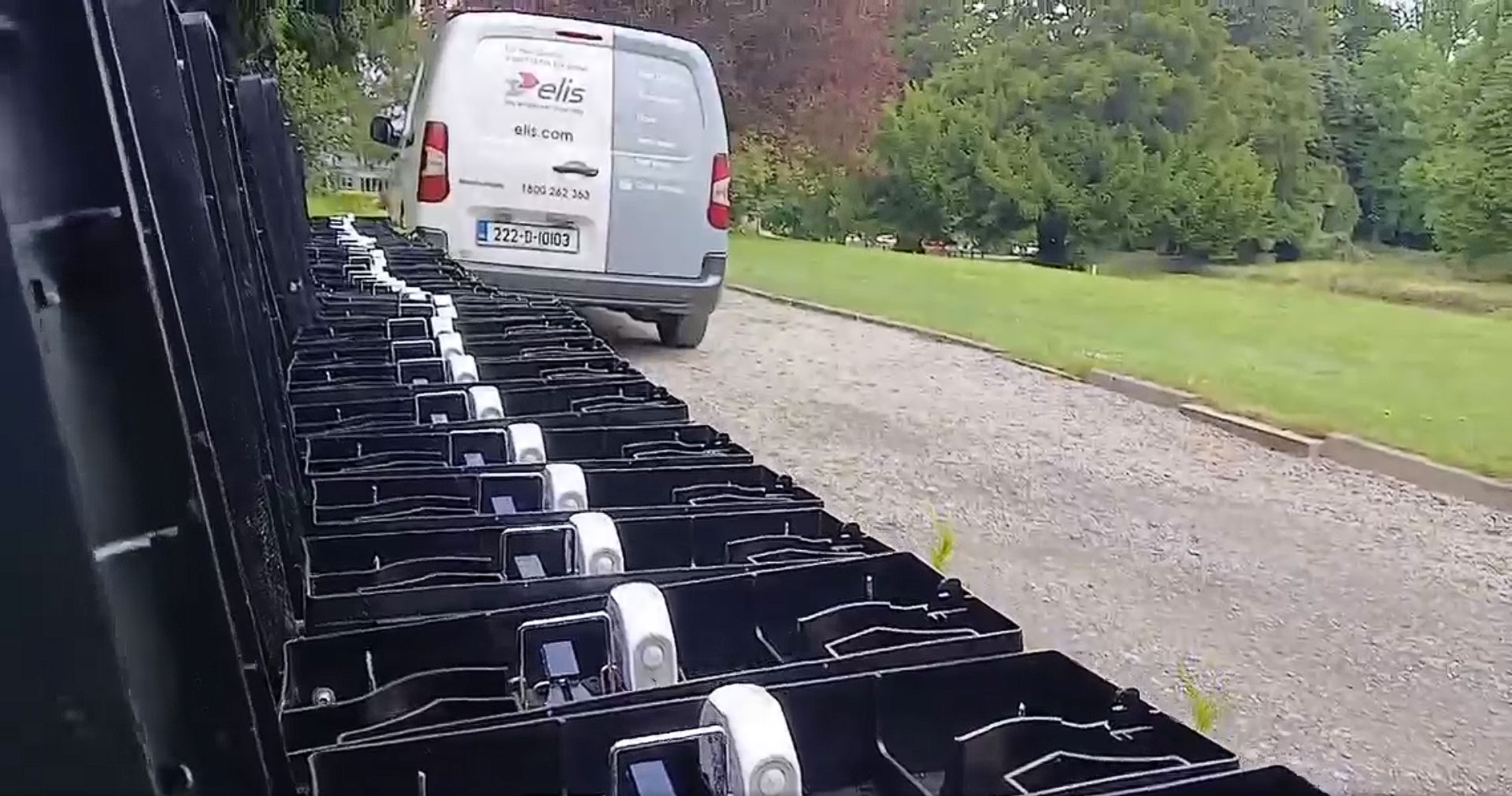 Rows of EverSmart Pest bait stations installed along a golf course path with an Elis service van