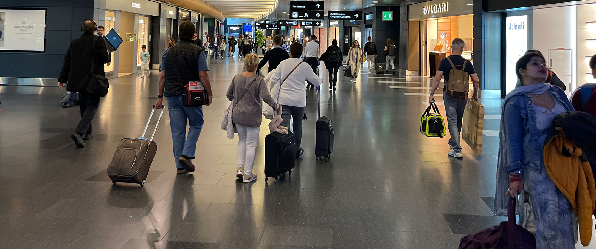 Travelers with luggage walking through a busy airport terminal concourse